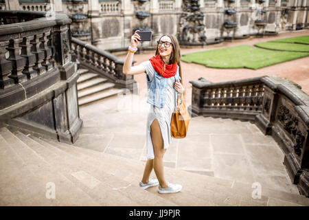 Young woman tourist photographing with phone visiting the old palace in Dresden city, Germany Stock Photo