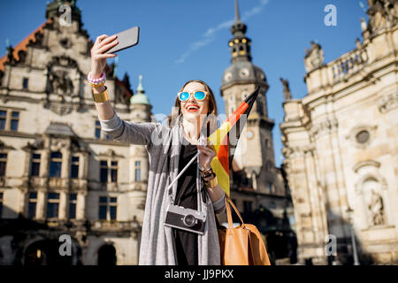 Young woman tourist making selfie photo with german flag in the old town of Dresden, Germany Stock Photo