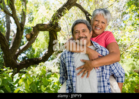 Portrait of happy senior man giving piggy bag to woman on a sunny day Stock Photo