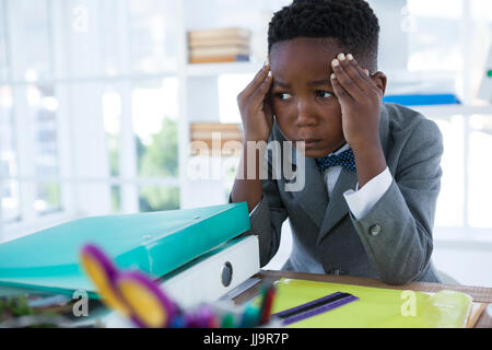 Businessman with head in hand looking away while sitting at desk in office Stock Photo