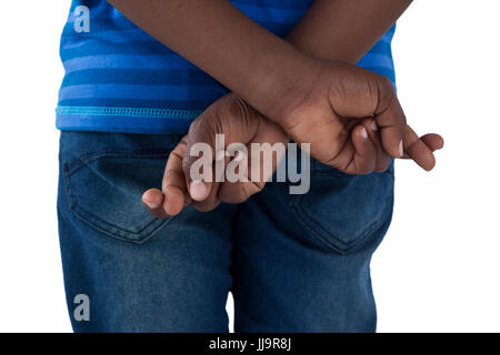 Mid-section of boy holding his fingers crossed against white background Stock Photo