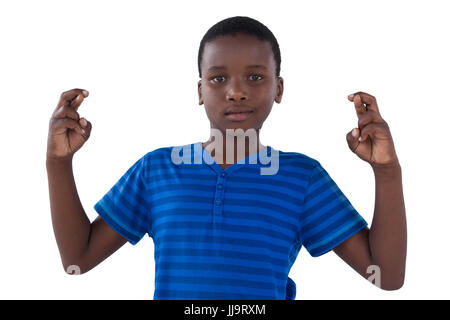 Portrait of cute boy holding his fingers crossed against white background Stock Photo