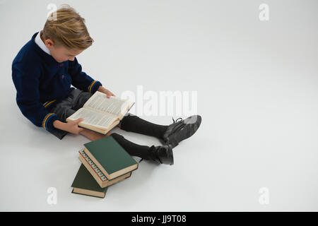 Attentive schoolboy reading book on white background Stock Photo - Alamy