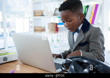 Businessman using laptop at desk by bookshelf in office Stock Photo
