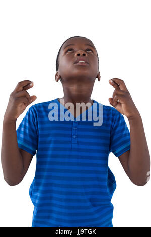 Close-up of cute boy holding his fingers crossed against white background Stock Photo