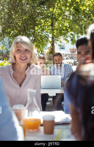 Friends interacting with each other and using laptop in restaurant Stock Photo
