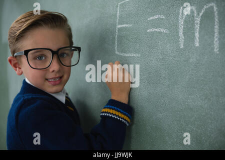 Portrait of schoolboy writing maths formula on chalkboard Stock Photo