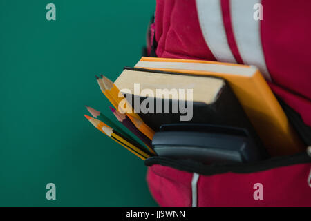 Close-up schoolbag with various supplies on green background Stock Photo