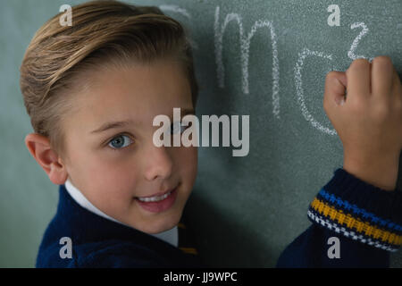 Portrait of schoolboy writing maths formula on chalkboard Stock Photo