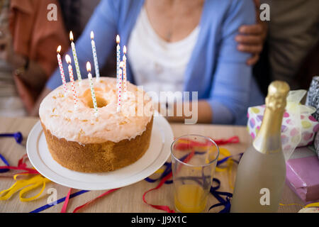 Close-up of candles on birthday cake with senior people in background Stock Photo