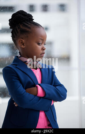 Thoughtful businesswoman with arms crossed standing by window at office Stock Photo