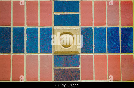 red, tan and blue cross pattern on brick wall Stock Photo