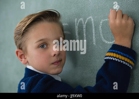 Portrait of schoolboy writing maths formula on chalkboard Stock Photo