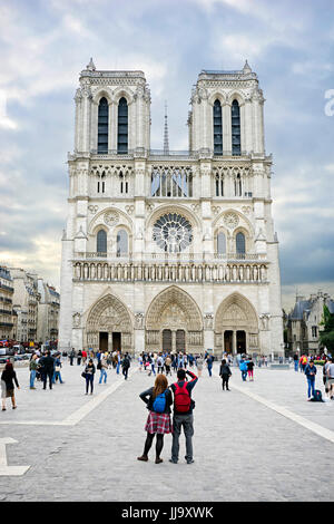 Tourist couple taking a photo of Notre Dame Cathedral at sunrise, Paris, France Stock Photo