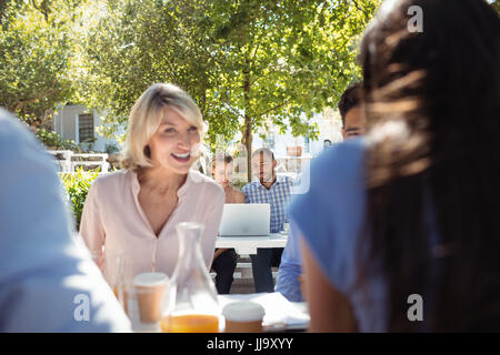 Smiling friends interacting with each other in restaurant Stock Photo