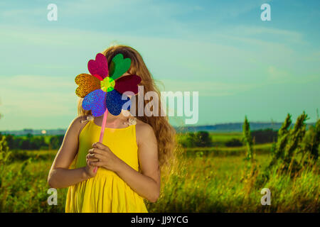 Girl in a field on the road in a yellow dress.  Color Pinwheel. Stock Photo