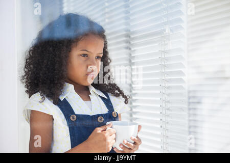 Thoughtful businesswoman holding coffee cup seen through window Stock Photo