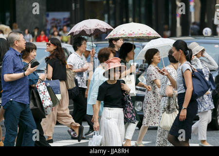 Tokyo, Japan. 19th July, 2017. Pedestrians holding parasols walk in summer heat in Ginza shopping district on July 19, 2017, Tokyo, Japan. The Japanese Meteorological Agency announced the end of the rainy season in Tokyo and surrounding prefectures. This year the rainy season ended earlier in Kanto, Koshin and Tokai regions. Credit: Rodrigo Reyes Marin/AFLO/Alamy Live News Stock Photo