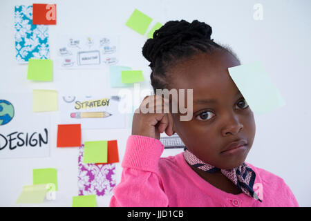 Thoughtful businesswoman with adhesive notes against whiteboard in office Stock Photo