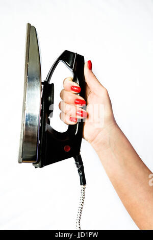Old vintage iron in a graceful female hand with red nails on a white background. Stock Photo