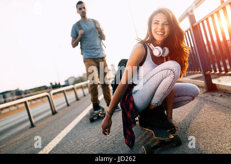 Young attractive couple riding skateboards and having fun Stock Photo