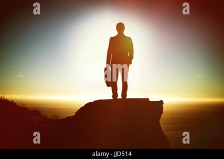 Silhouette businessman holding briefcase  against scenic view of mountain by sea against sky Stock Photo