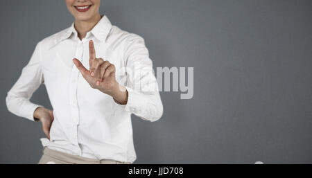Mid section of smiling businesswoman using invisible screen against grey background Stock Photo