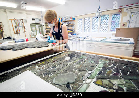 Rachel Thomas from York Glaziers, Britain's oldest and largest specialist stained glass conservation studio who celebrate their 50th anniversary tomorrow, restores one of the final panels or York Minster's Great East Window, the largest medieval stained glass window in England. Stock Photo