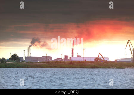 Air pollution by smoke coming out of two factory chimneys. Industrial zone in the city Stock Photo