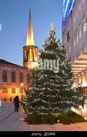 BBC broadcasting house Christmas tree & lights in the new large courtyard with floodlit spire of All Souls Church Langham Place beyond London UK Stock Photo