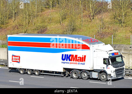 UKMail express parcels & mail logistics articulated trailer & hgv truck lorry driving along English motorway Essex England UK includes advert for ipost Stock Photo