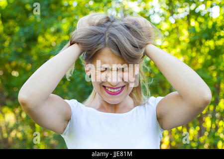 Picture of a very angry young woman having a breakdown  holding her head and hair outdoor Stock Photo