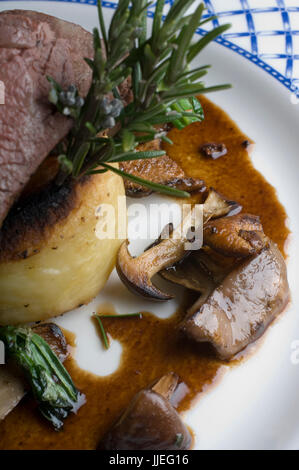 A Plate of Succulent Roast Lamb with Sauteed chanterelle mushrooms with a rosemary gravy Stock Photo