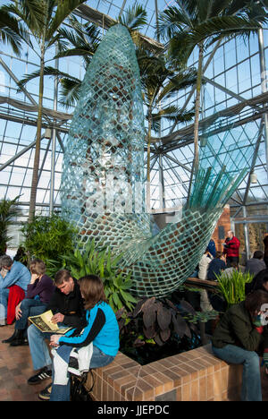Visitors to the  Cowles Conservatory sit below The Standing Fish, a scuplture by Frank Gehry, in the Sculpture Garden at the Walker Art Center,  Minneapolis, Minnesota. Stock Photo