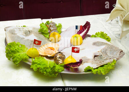 Close Up detail of Metal tray of fish and crustaceans, Oysters, shrimp, scallops and ray with lemon salad and flags on toothpick in Italian restaurant Stock Photo