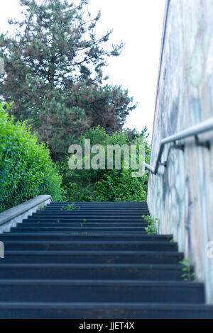 Concrete staircase of the underpass with Metal handrails and murals on wall In the suburbs italian city Stock Photo