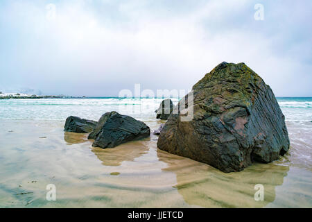 Sunrise on the sandy shore of the ocean and mountains with snow on the horizon Stock Photo