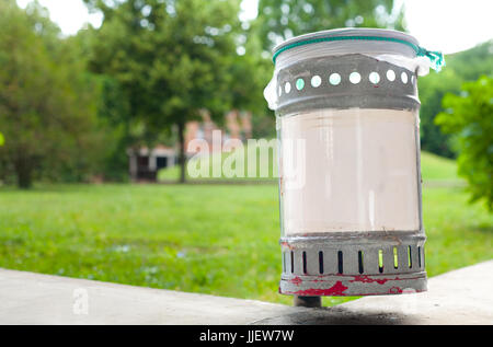 Small iron garbage can in public park with white plastic sign editable text Stock Photo