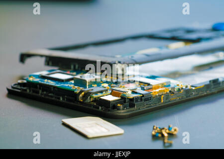 Disassembled mobile phone in the service center with internal components of the camera and speaker Stock Photo