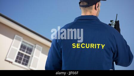 Digital composite of Security man in front of a house holding a talkie-walkie Stock Photo