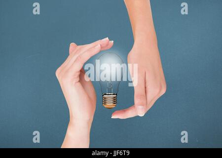 Digital composite of bulb on hands Stock Photo