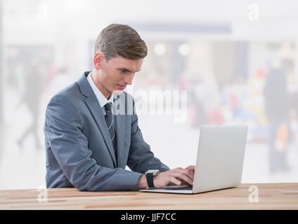 Digital composite of Businessman on laptop in bright shopping mall Stock Photo