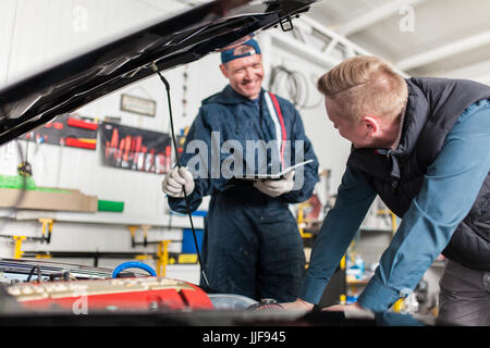 Sports car in a service workshop - two mechanics inspecting the engine Stock Photo