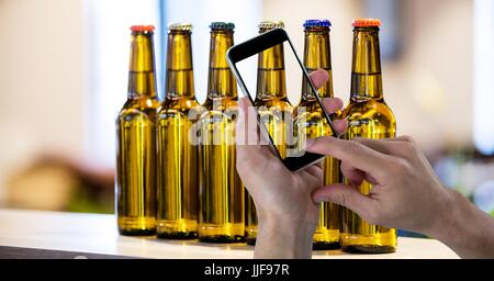 Digital composite of Hand taking picture of beer bottles through smart phone Stock Photo