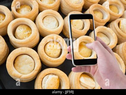 Digital composite of Hand of person taking a picture of cakes with her smartphone Stock Photo