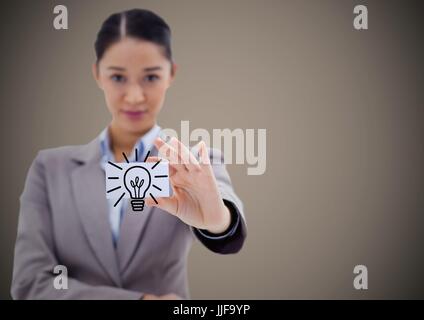 Digital composite of Business woman holding out card showing lightbulb graphic against brown background Stock Photo