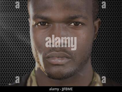 Digital composite of foreground of serious soldier looking us. Dark background and flares Stock Photo
