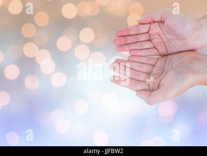Digital composite of Hands open together with sparkling light bokeh background Stock Photo