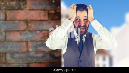 Digital composite of Worried hipster man with his hands on his head in front of a red wall Stock Photo