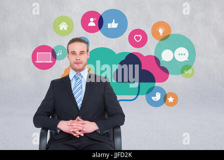 Digital composite of business man sitting in chair with icons on the wall Stock Photo
